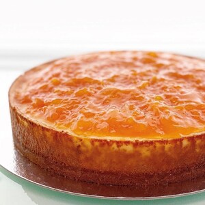 May include: A round orange cheesecake topped with a layer of orange marmalade.