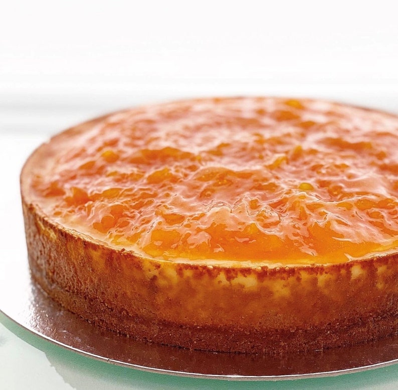 May include: A round orange cheesecake topped with a layer of orange marmalade.