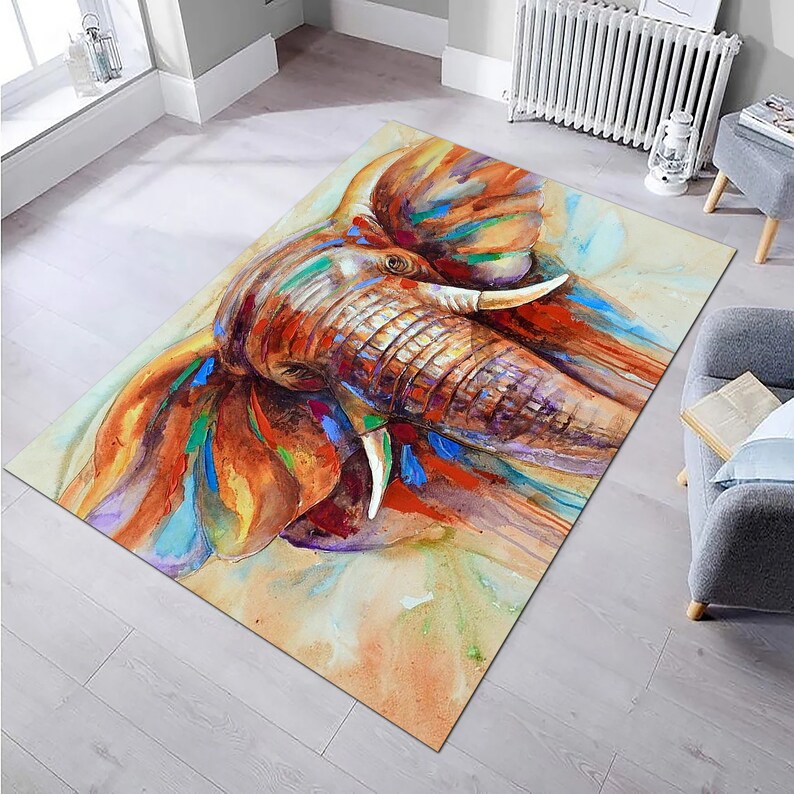 May include: A watercolor painting of an elephant's head with splashes of orange, blue, green, and purple paint. The elephant's trunk is raised and its tusks are visible.