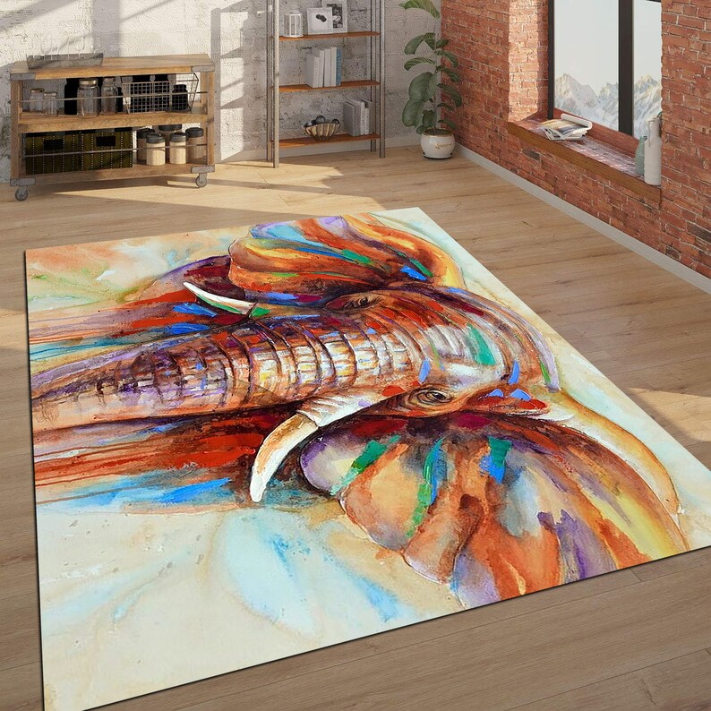 May include: A watercolor painting of an elephant's face with splashes of blue, green, orange, and red paint. The elephant's trunk is raised and its eyes are closed.