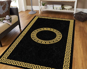 May include: Black and gold area rug with a Greek key border and a large circular Greek key design in the center.