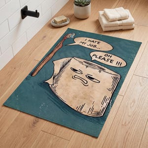 Könnte beinhalten: Eine rechteckige, blaugrüne Badematte mit einer Cartoon-Illustration einer Toilettenpapierrolle mit mürrischem Gesicht und einer Holzzahnbürste. Sprechblasen enthalten den Text I HATE MY JOB und OH PLEASE. Das Design ist auf strukturiertem Stoff gedruckt.
