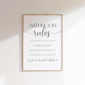 Puede incluir: Un cartel blanco con texto negro que dice "BATHROOM rules" y enumera las reglas del baño: "IF YOU LIFT IT, PUT IT DOWN", "IF IT SMELLS, SPRAY IT", "IF IT RUNS OUT, REPLACE IT", "IF YOU SPILL IT, CLEAN IT UP", "if you're finished. flush it"
