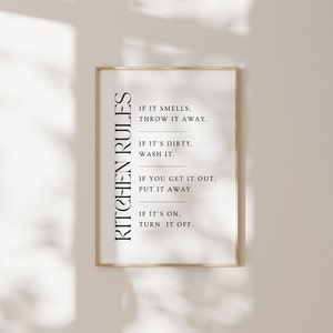 May include: A gold framed print with the text "KITCHEN RULES" in black vertical text. The print includes four rules: "If it smells, throw it away.", "If it's dirty, wash it.", "If you get it out, put it away.", and "If it's on, turn it off."