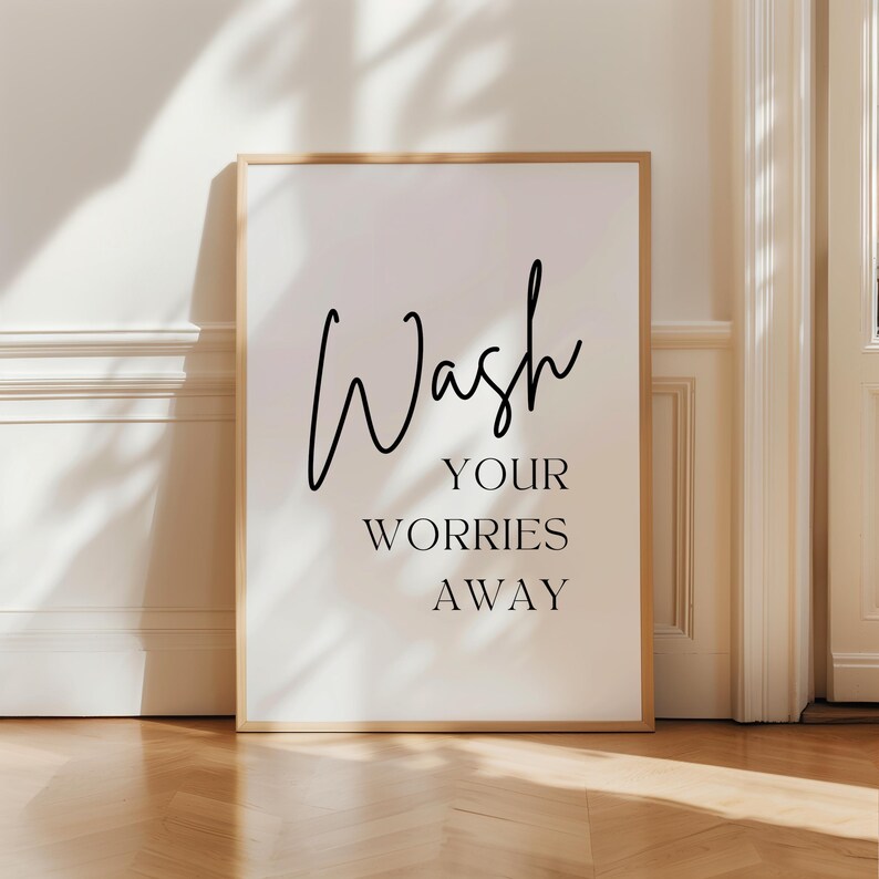May include: A white framed print with black text that reads "Wash your worries away".