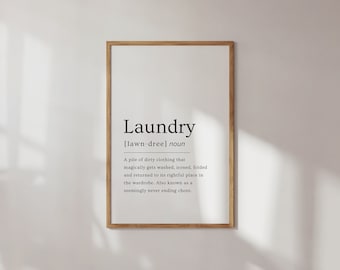 May include: A framed print with a white background and black text that reads "Laundry [lawn-dree] noun A pile of dirty clothing that magically gets washed, ironed, folded and returned to its rightful place in the wardrobe. Also known as a seemingly never ending chore."