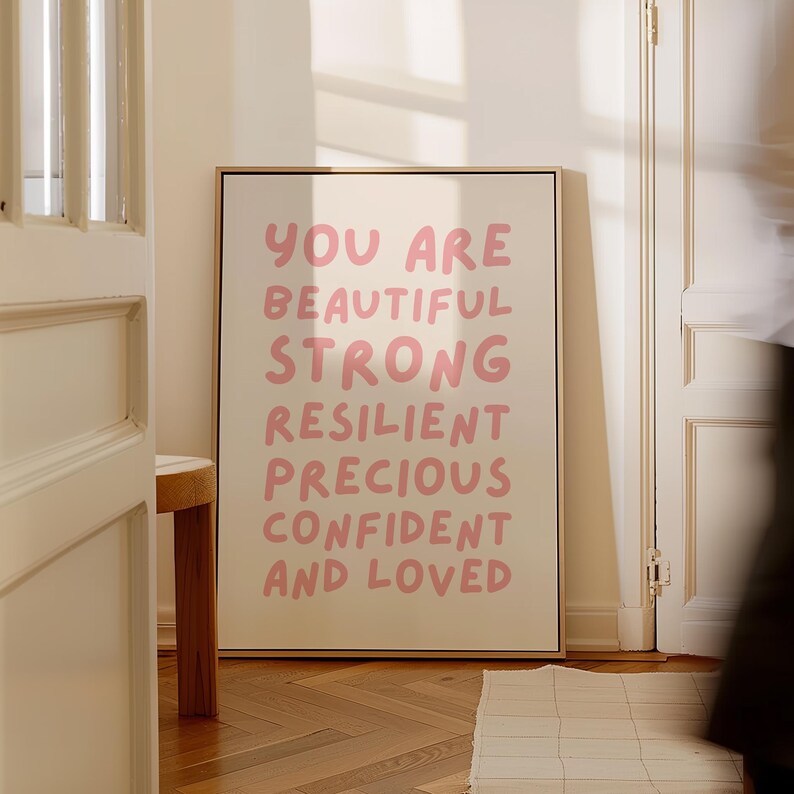 May include: A beige canvas print with a pink message that reads "You are beautiful strong resilient precious confident and loved".