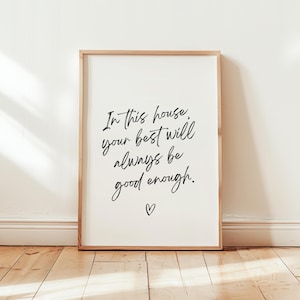 May include: A framed print with a white background and black text that reads "In this house, your best will always be good enough." A small heart symbol is below the text.