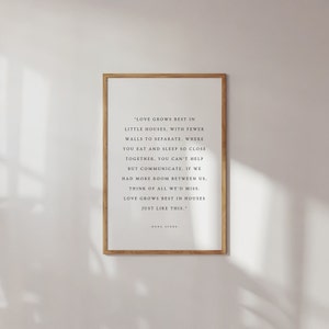 Peut inclure: Une impression encadrée avec un fond blanc et du texte noir. Le texte dit : "L'amour grandit mieux dans les petites maisons, avec moins de murs pour séparer. Là où vous mangez et dormez si près l'un de l'autre, vous ne pouvez pas vous empêcher de communiquer. Si nous avions plus d'espace entre nous, pensez à tout ce que nous manquerions. L'amour grandit mieux dans les maisons comme celle-ci." - Doug Stone.