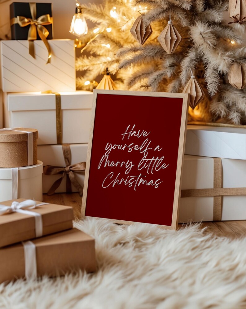 May include: A framed red sign with the text "Have yourself a Merry little Christmas" in white script. The sign is in front of a Christmas tree and wrapped gifts.
