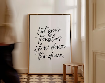 May include: A white framed print with black calligraphy that reads "Let your troubles flow down the drain."