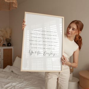 May include: A framed print with a light wood frame. The white background features black script text that reads, "So it's not gonna be easy... I want all of you, forever, every day." The print is held by a person.