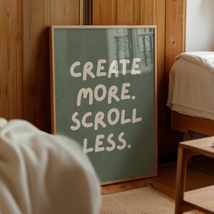 May include: A framed print with a green background and white text that reads "CREATE MORE. SCROLL LESS."
