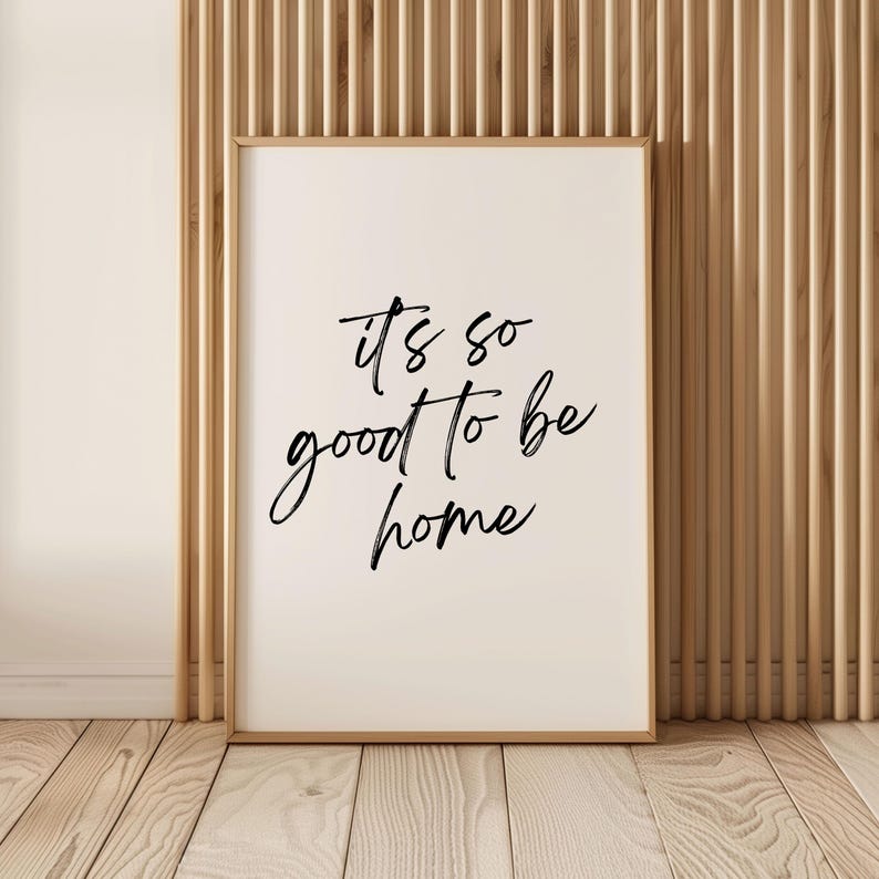 May include: A white framed print with black calligraphy that reads "it's so good to be home".