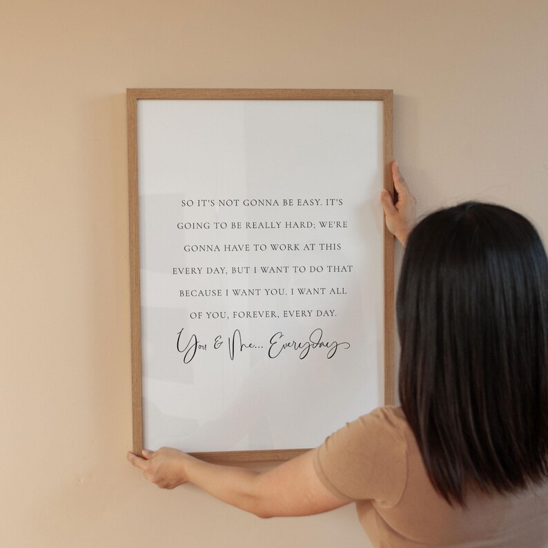 May include: A framed print with a light wood frame. The white background features black text that reads, "So it's not gonna be easy... You & Me... Everyday."