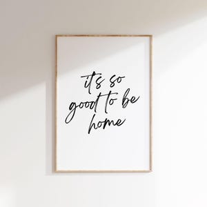 May include: A black and white printable wall art print with the text "It's so good to be home" in a handwritten font.