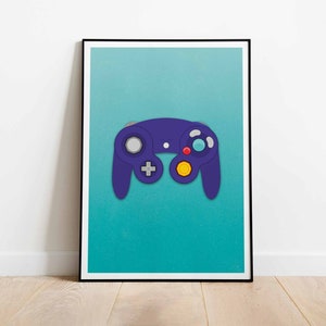 Puede incluir: Una impresión enmarcada con un mando de videojuegos morado sobre un fondo turquesa. El mando tiene botones grises, amarillos, rojos y azules. La impresión está en un marco negro y se muestra contra una pared blanca.