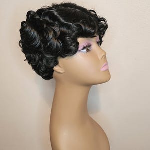 May include: A black wig with short, curly hair styled in a vintage look. The wig is on a mannequin head.