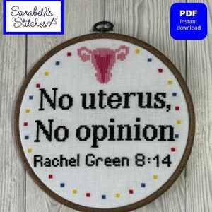May include: A white embroidery hoop with a brown wooden frame. The embroidery features a pink uterus with the text "No uterus, No opinion. Rachel Green 8:14".