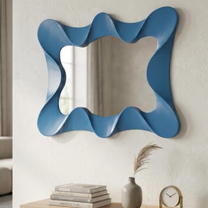 May include: A wall mirror featuring a distinctive sky blue frame with a continuous, undulating, wave-like design. The frame has a smooth, matte finish and surrounds a rectangular reflective glass surface with rounded corners and curved edges.
