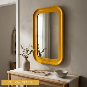 Könnte beinhalten: Ein rechteckiger Wandspiegel mit einem glatten, glänzenden senfgelben Rahmen mit abgerundeten Ecken. Der Spiegel reflektiert einen hellen Innenraum, und der Text "YELLOW FRAME" ist in einem gelben Feld unten links zu sehen.