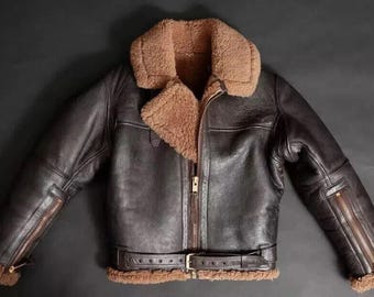 May include: A brown leather jacket with a shearling collar and lining. The jacket features a front zipper, zippered sleeves, and a waist belt with a buckle. The jacket is a classic style, perfect for cold weather.