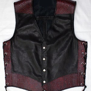 May include: A black leather vest with red crocodile-embossed leather panels on the collar, bottom, and sides. The vest has a V-neck, button closure, and lace-up sides.