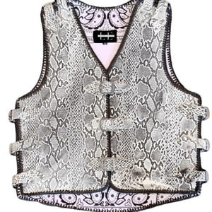 Può includere: Un giubbotto in pelle bianca con motivo a serpente, cuciture e fibbie nere. Il giubbotto è foderato con un bandana paisley.