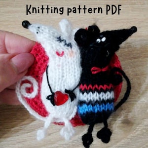 May include: Knitting pattern PDF for a white and black mouse amigurumi toy. The white mouse holds a red heart and the black mouse has a red bow tie. Both mice are sitting on a red knitted circle.