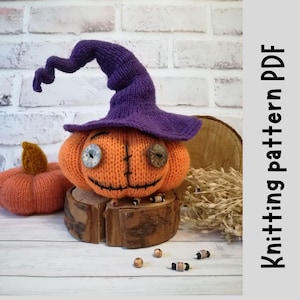 May include: Knitted orange pumpkin with a purple knitted witch hat, stitched facial features, and button eyes. The pumpkin is sitting on a wooden stump with brown beads scattered around it.