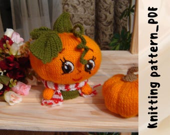Può includere: Una bambola di zucca arancione lavorata a maglia con un viso sorridente, foglie verdi e una sciarpa rossa e bianca. Accanto c'è una zucca più piccola lavorata a maglia. Il testo "Knitting pattern_PDF" è a destra.