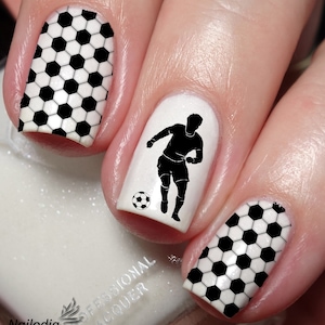 May include: Black and white nail art featuring a football pattern and a silhouette of a footballer. The nail art is applied to a set of fingernails.