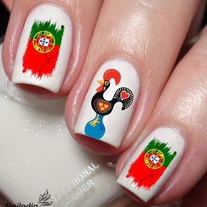 Può includere: Primo piano di unghie con nail art che presenta la bandiera portoghese e un design a forma di gallo. Il gallo è nero, rosso e blu con accenti bianchi. La bandiera è rossa, verde e gialla con uno scudo bianco.