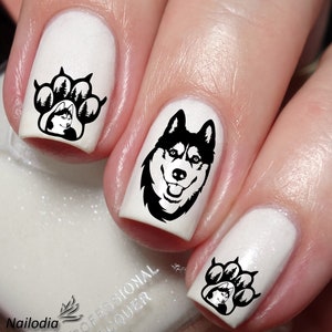 Puede incluir: Uñas pintadas de blanco con arte de uñas en blanco y negro que presenta un perro husky y huellas de patas con pinos.