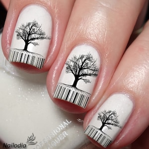Puede incluir: Esmalte de uñas blanco con diseños de árboles en blanco y negro y códigos de barras en cada uña.