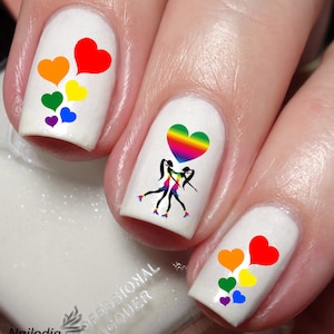 May include: Nail art featuring two women holding a rainbow heart balloon. The nail art is on a white background and includes a rainbow heart balloon and two women holding hands. The nail art is a great way to show your pride.