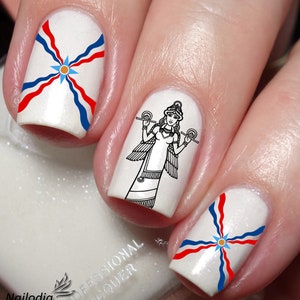 May include: White nail polish with a design of the Kurdish flag and a black and white illustration of a winged woman holding a scale.