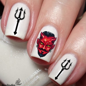 Può includere: Smalto per unghie bianco con adesivi per nail art neri e rossi. Gli adesivi raffigurano una testa di diavolo con corna e barba, e un tridente.