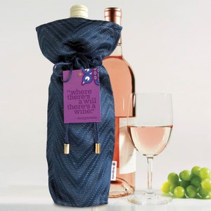 May include: A navy blue wine bottle bag with a chevron pattern, drawstring closure, and gold-colored accents. A purple tag reads "where there's a will there's a wine." A glass of rosé and a bunch of green grapes are also visible.