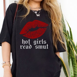 Model is wearing comfort colors oversized tee in black with hot girls read smut in white and lipstick print in red