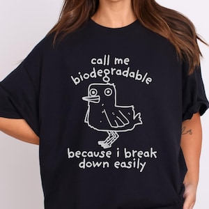 May include: Black oversized t-shirt with a white graphic of a bird and the text "call me biodegradable because i break down easily"