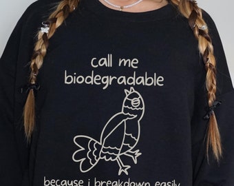 May include: Black sweatshirt with a white graphic design that says "Call me biodegradable because I breakdown easily" and features a cartoon bird.