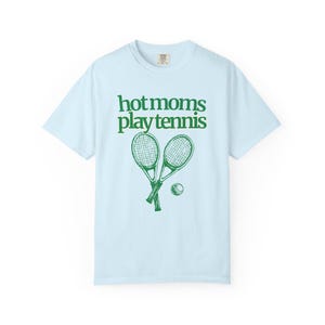 model is wearing comfort colors short sleeve shirt in orchid (light purple) with hot moms play tennis graphic in green on front