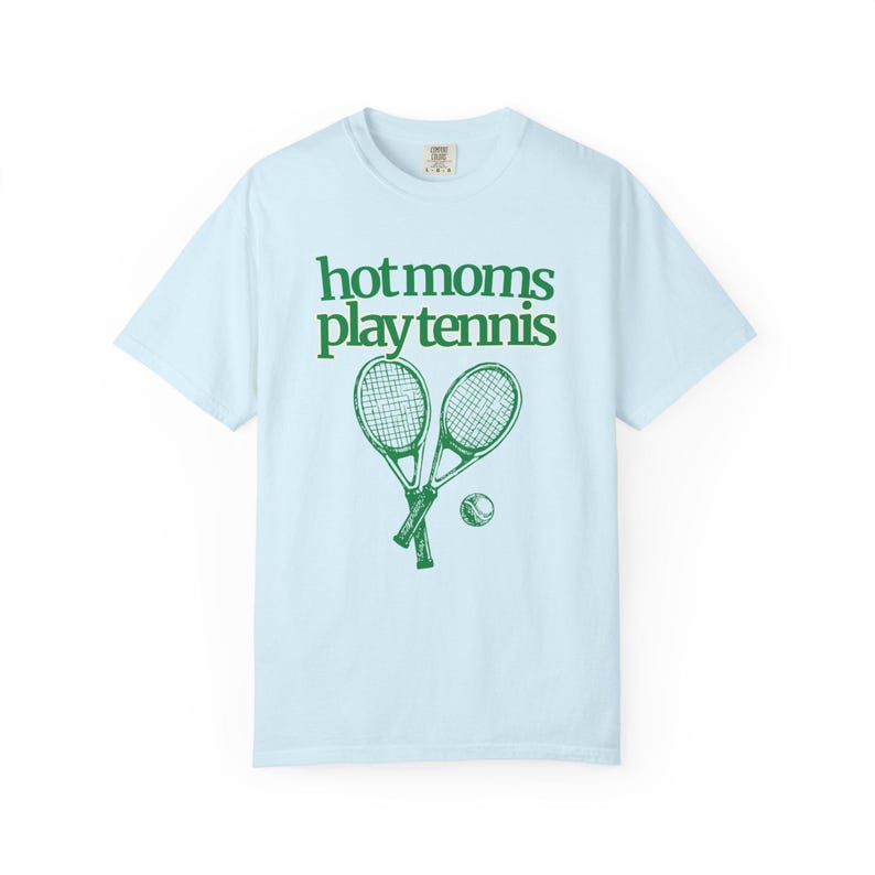 model is wearing comfort colors short sleeve shirt in orchid (light purple) with hot moms play tennis graphic in green on front