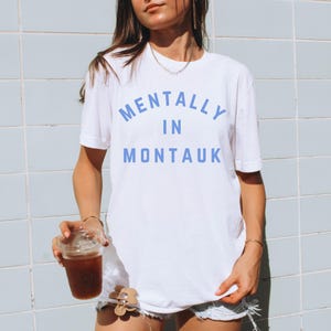 May include: White t-shirt with blue text that reads "Mentally in Montauk".