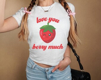 Op de afbeelding: Wit gecropped T-shirt met een rode aardbei-afbeelding en de tekst "love you berry much".