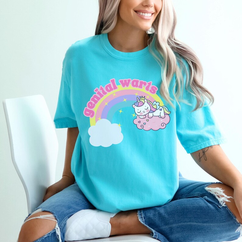 model is wearing comfort colors tee in lagoon blue with genital warts design on front with a rainbow stars and a unicorn