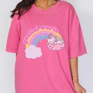 model is wearing comfort colors tee in crunchberry with genital warts design on front with a rainbow stars and a unicorn