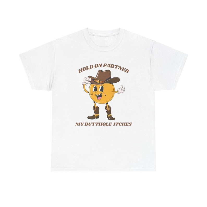 Model is wearing a gildan tee shirt in white with a smiling cowboy giving a thumbs up and it says hold on partner my butthole itches on front in brown