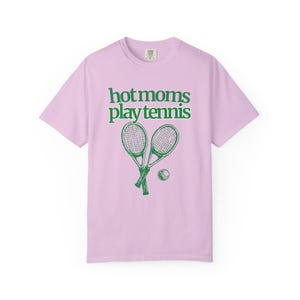model is wearing comfort colors short sleeve shirt in flo blue with hot moms play tennis graphic in pink on front